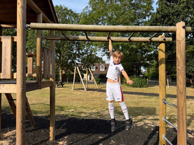 Lucas hanging from a playground climbing bar in an England football kit