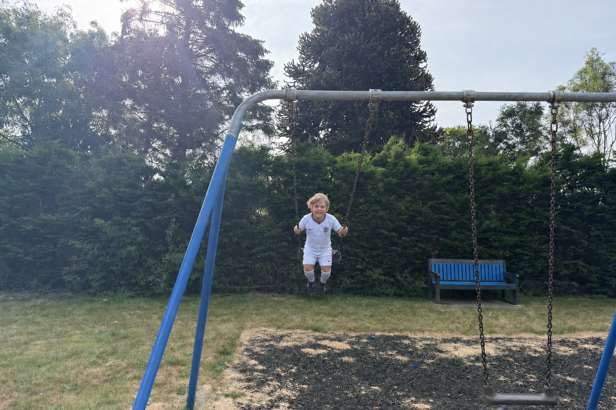 Lucas smiling while swinging at the park